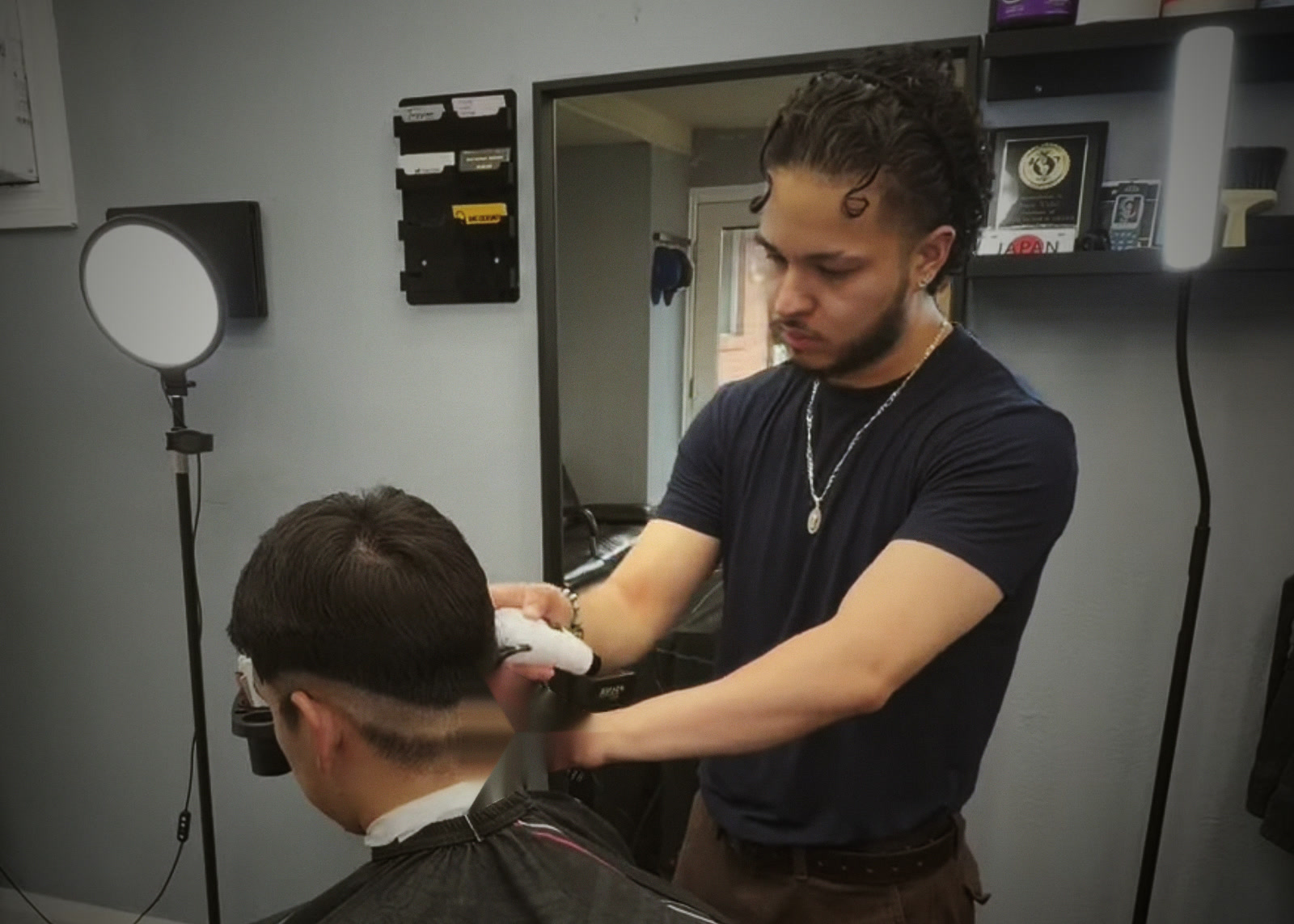 Juan cutting a client’s hair in his barbershop